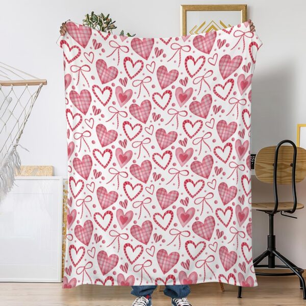 Pink hearts flannel fleece throw blanket draped on a couch for cozy bedroom and living room decor