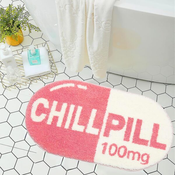 Pink chill pill-shaped bath mat with soft microfiber plush pile, absorbent surface, and non-slip TPR backing, designed as a fun novelty bathroom rug for showers, tubs, bedrooms, and playful pink room décor.