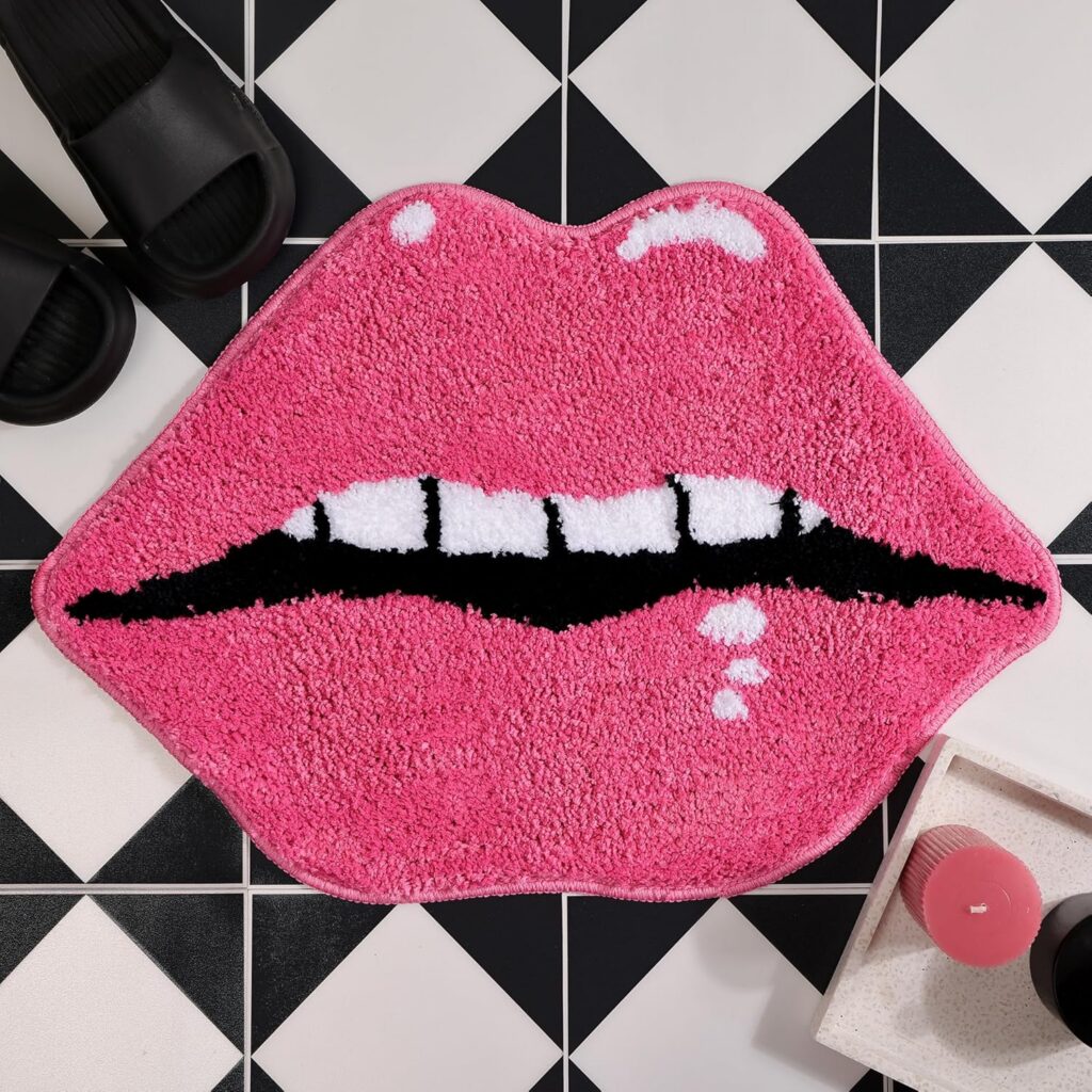 Pink lips-shaped plush bath mat with soft microfiber pile, absorbent surface, and non-slip backing, designed as a fun decorative bathroom rug for feminine, coquette, and playful room décor.