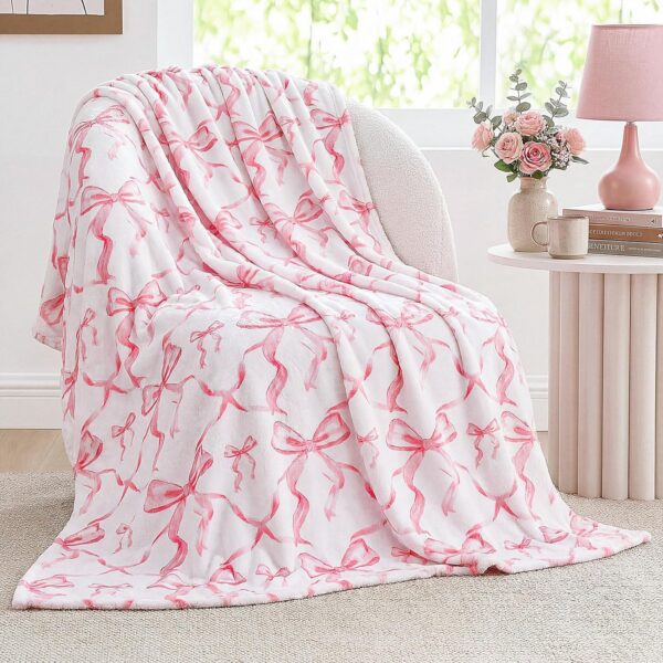Pink flannel throw blanket with an all-over bow print, featuring a soft lightweight design for beds, sofas, dorm rooms, and coquette-inspired bedroom décor.