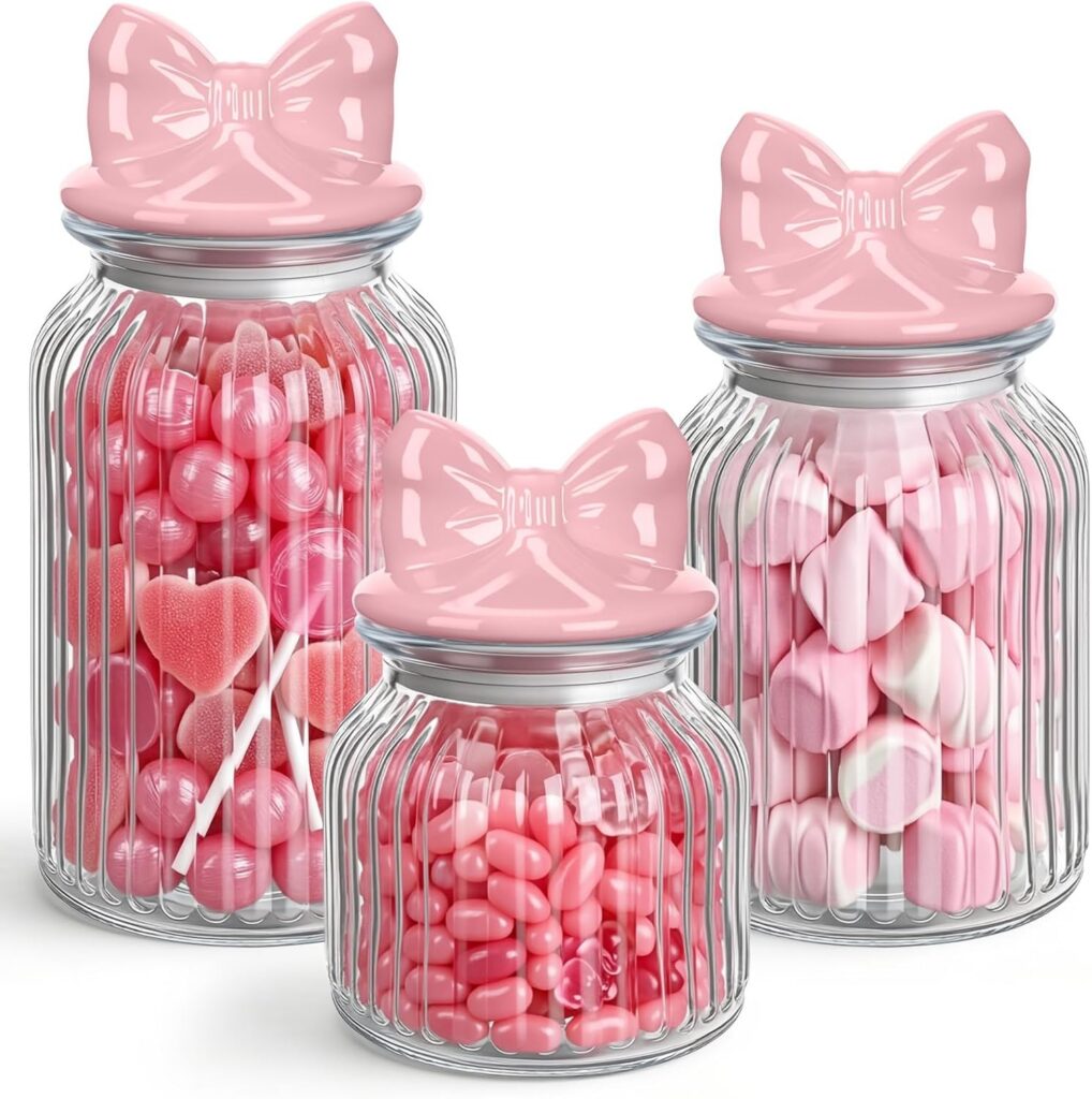 Set of three clear glass storage canisters with pink ceramic bow lids and airtight seals for storing cookies, candy, coffee beans, nuts, snacks, and other dry foods.