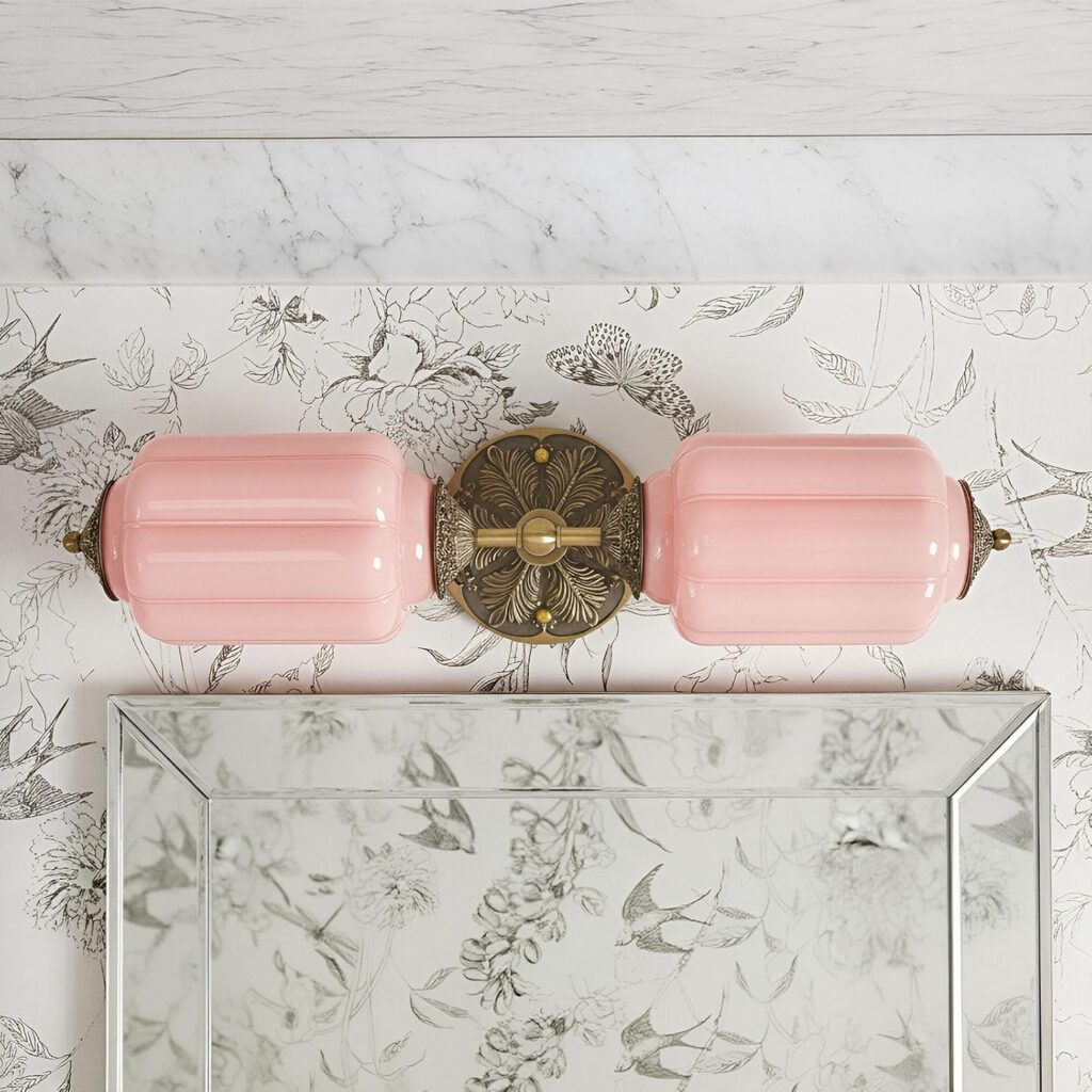 Vintage pink two-light wall sconce with hand-blown pink glass shades and a brass-finish metal base, designed for bathrooms, vanity mirrors, kitchens, bedrooms, and living spaces.